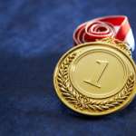 gold medal with ribbon on blue background